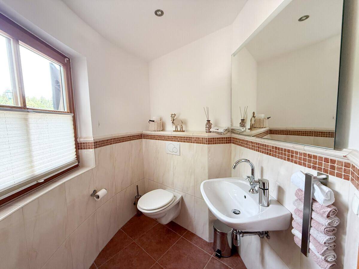 Helles Gäste-WC mit Fenster, wandhängendem WC und modernem Waschbecken.