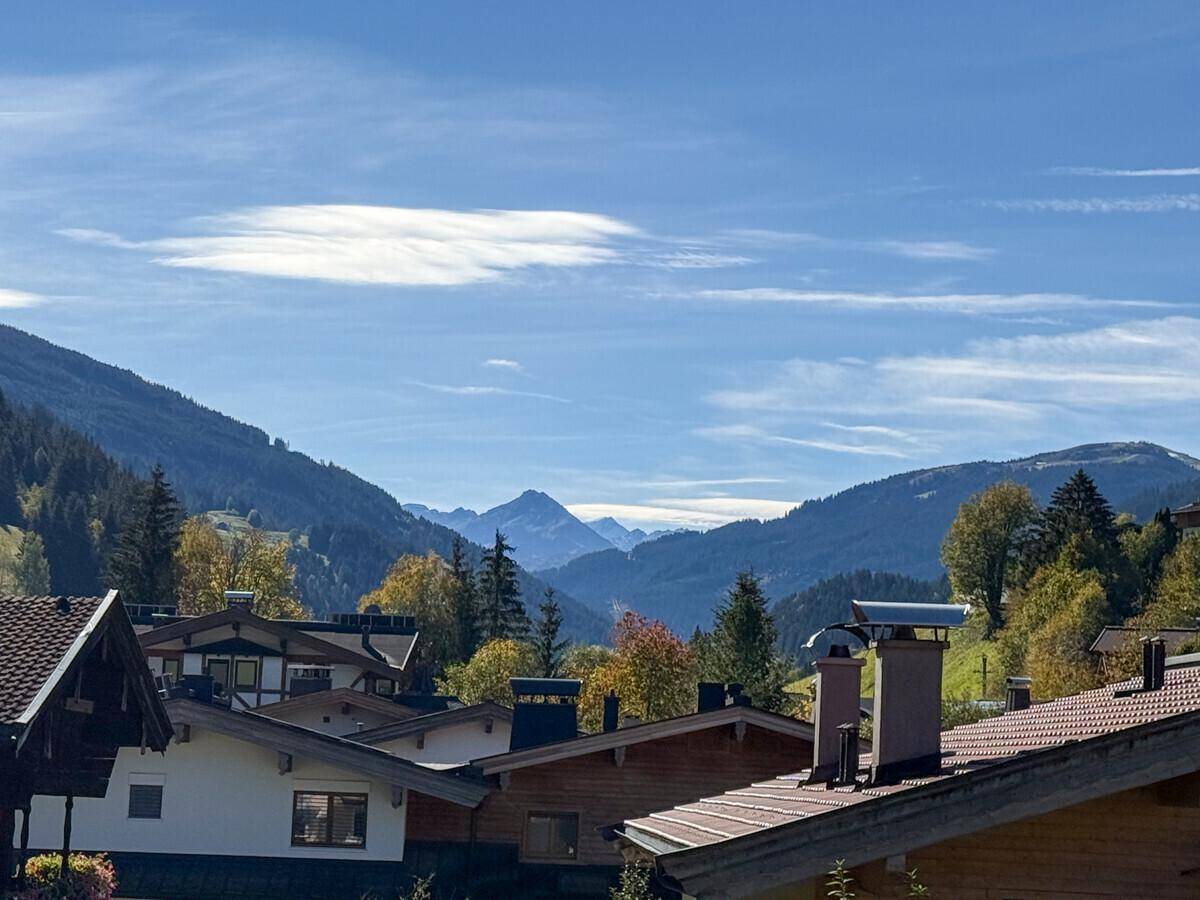 Malerischer Bergblick über Dächer und grüne Hügel unter blauem Himmel.