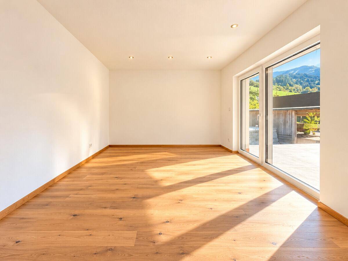Lichtdurchfluteter Raum mit Holzboden und großer Schiebetür zur Terrasse, bietet Bergblick.