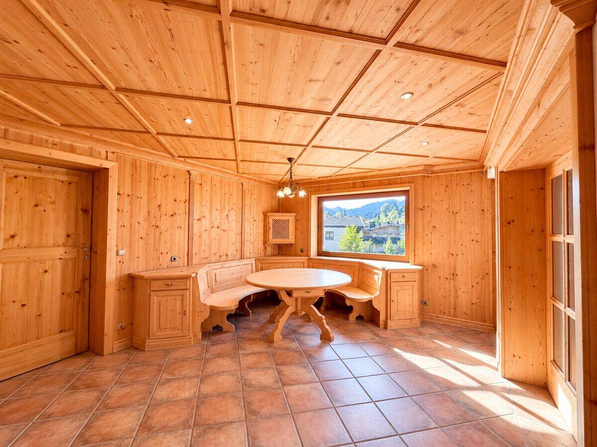 Gemütlicher Essbereich im alpenländischen Stil mit Holztäfelung, Eckbank und Blick auf die Berge.