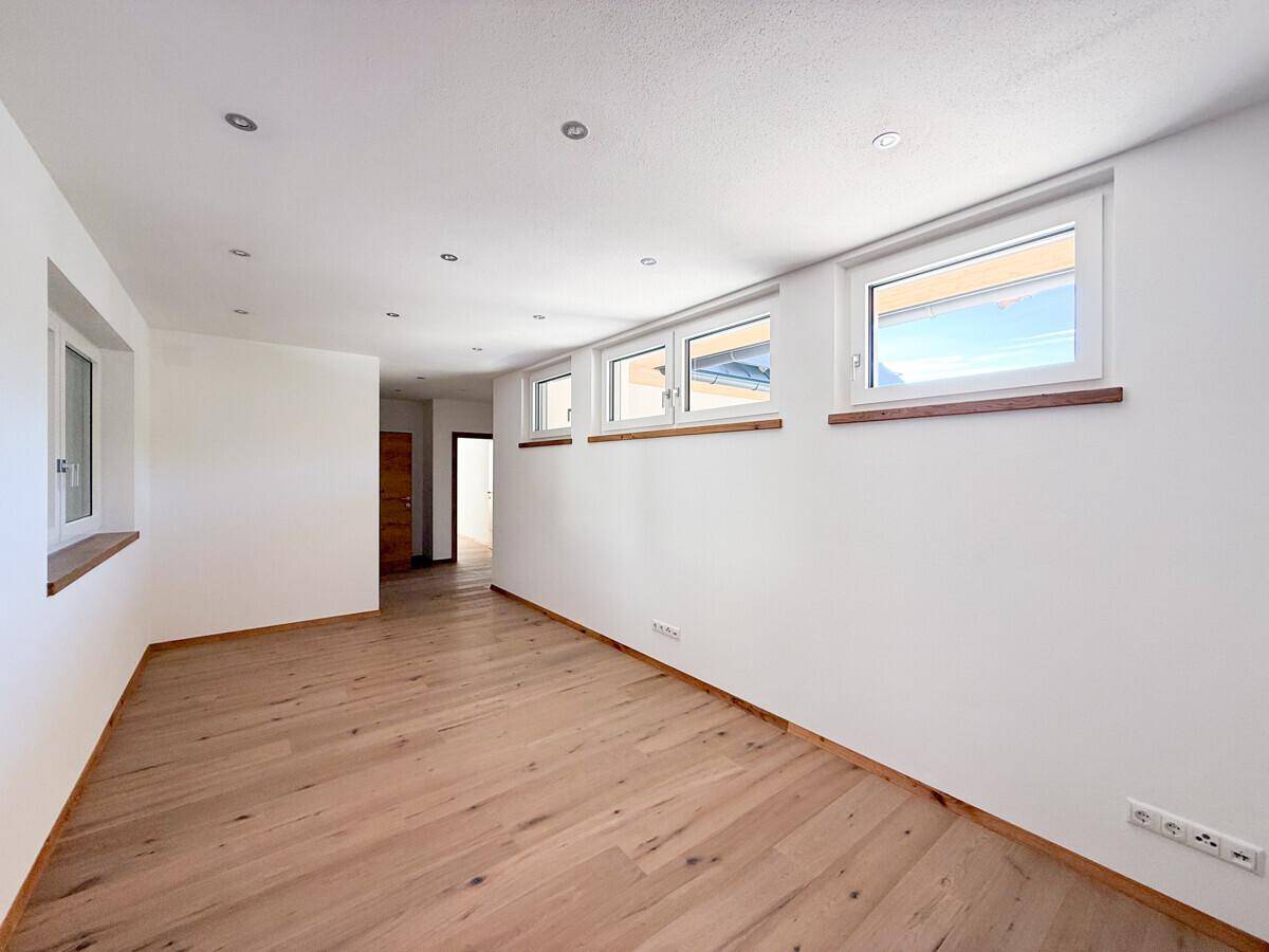 Heller Kellerraum mit Holzboden und mehreren Fenstern, vielseitig nutzbar.