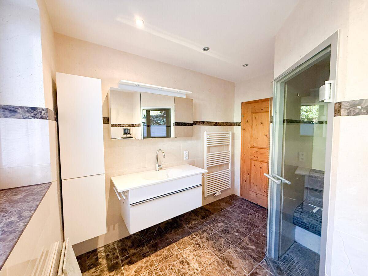 Badezimmer mit moderner Ausstattung, Einzelwaschbecken und integrierter Sauna für Wellness.