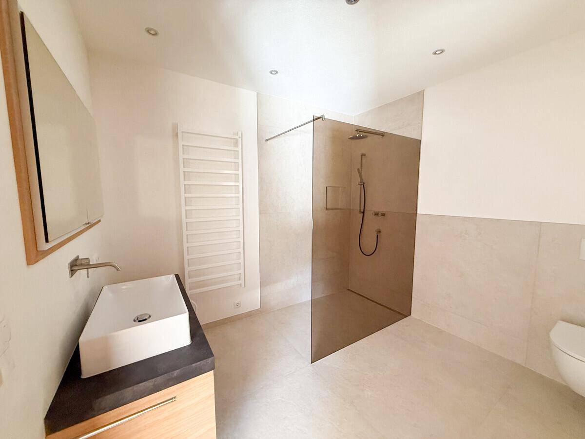 Modernes Badezimmer mit begehbarer Dusche, Einzelwaschbecken und beheiztem Handtuchhalter.