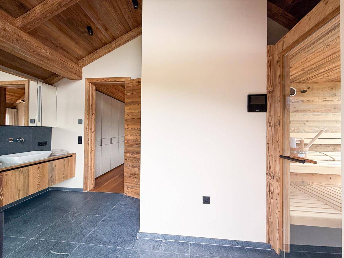 Modernes Badezimmer mit Waschtisch und direktem Zugang zu einer Holzsauna.