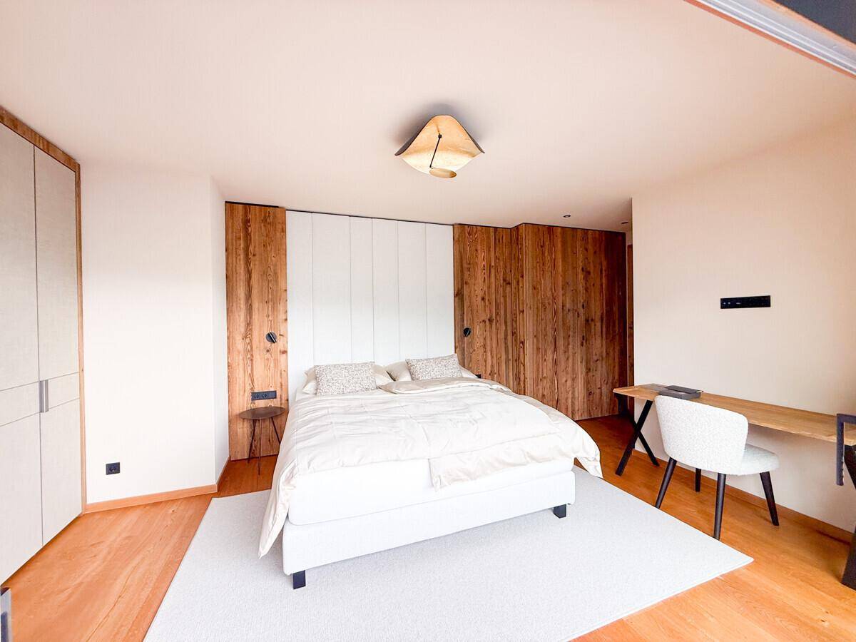 Gemütliches Schlafzimmer mit Holzwänden, Doppelbett und integriertem Schreibtischbereich.