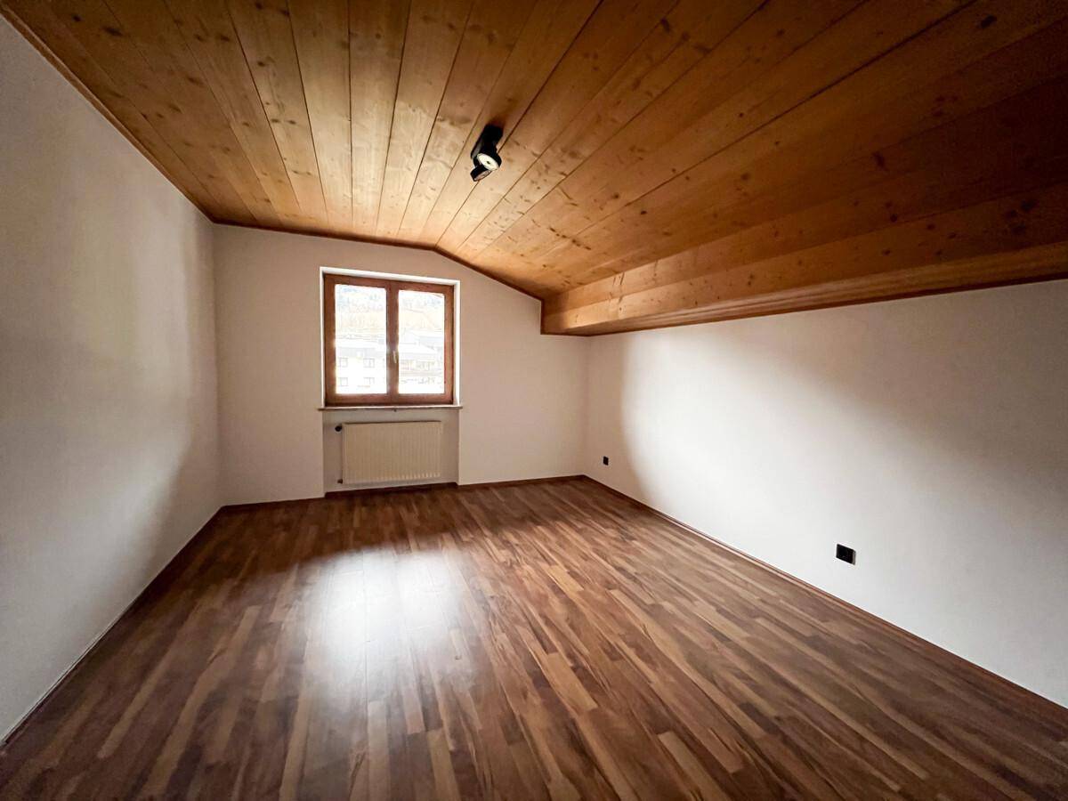 Schlafzimmer mit Holzdielenboden, Holzdecke und Fenster mit Blick ins Grüne.