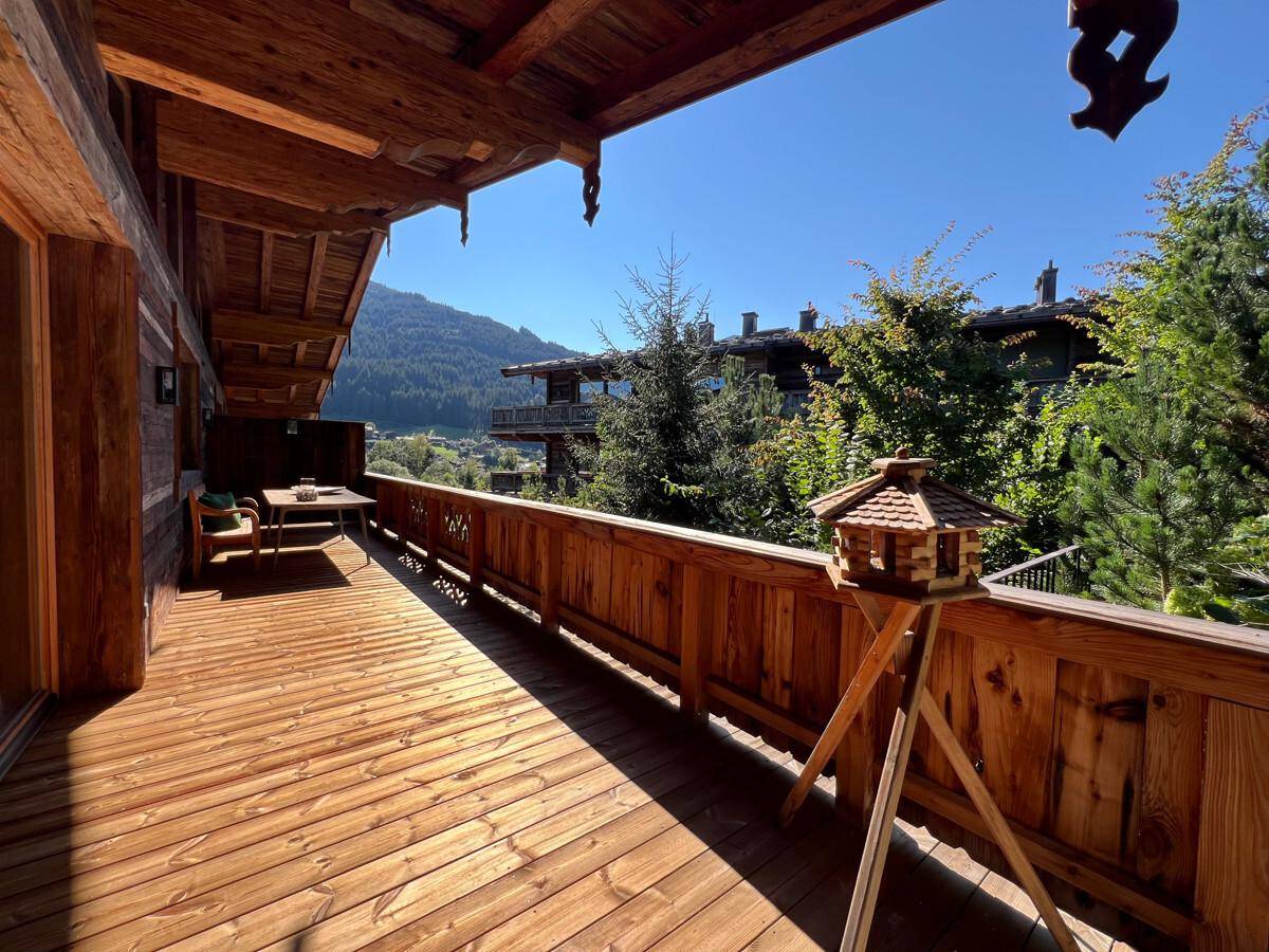 Geräumiger Holzbalkon mit Sitzgelegenheiten und malerischem Blick auf die Berge und das Tal.