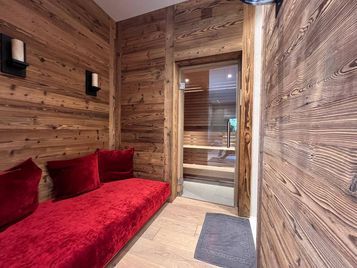 Entspannender Wellnessbereich mit rotem Sofa und Zugang zu einer Sauna.