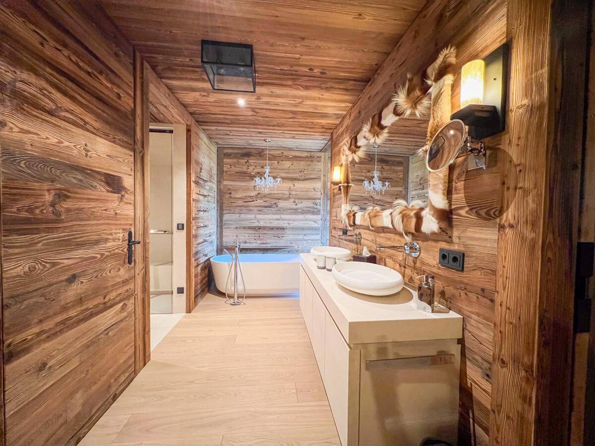 Elegantes Badezimmer mit Holzwänden, freistehender Badewanne und Doppelwaschbecken.