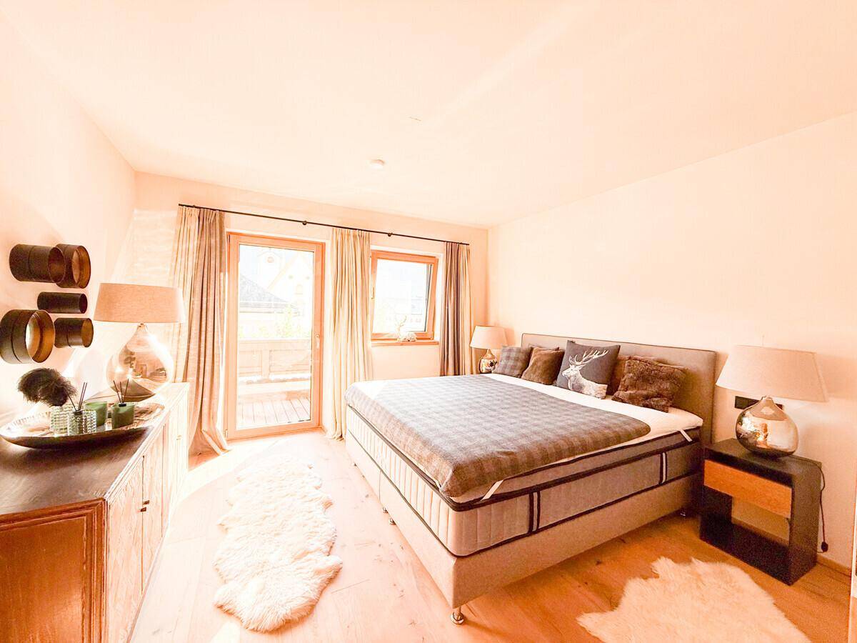 Helles Schlafzimmer mit großem Bett, Holzboden und direktem Zugang zum Balkon.