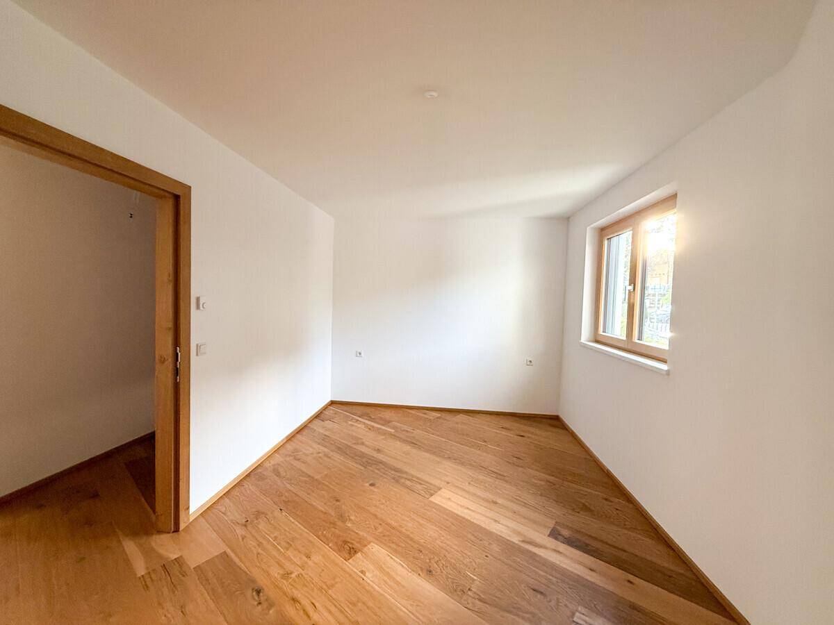 Leerer Raum mit Holzboden und Fenster, bereit für individuelle Gestaltung.