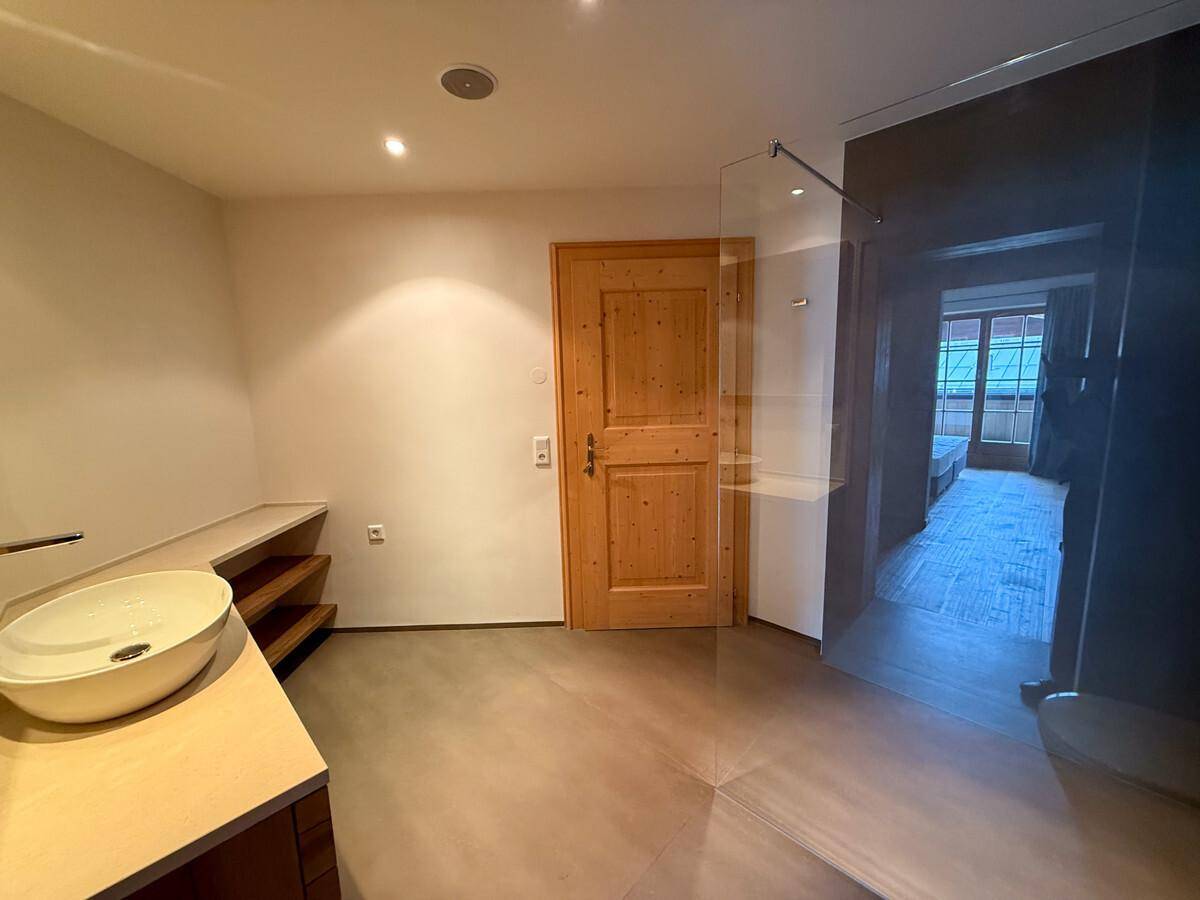 Helles Badezimmer mit modernem Waschtisch, Holzdetails und großer Dusche.