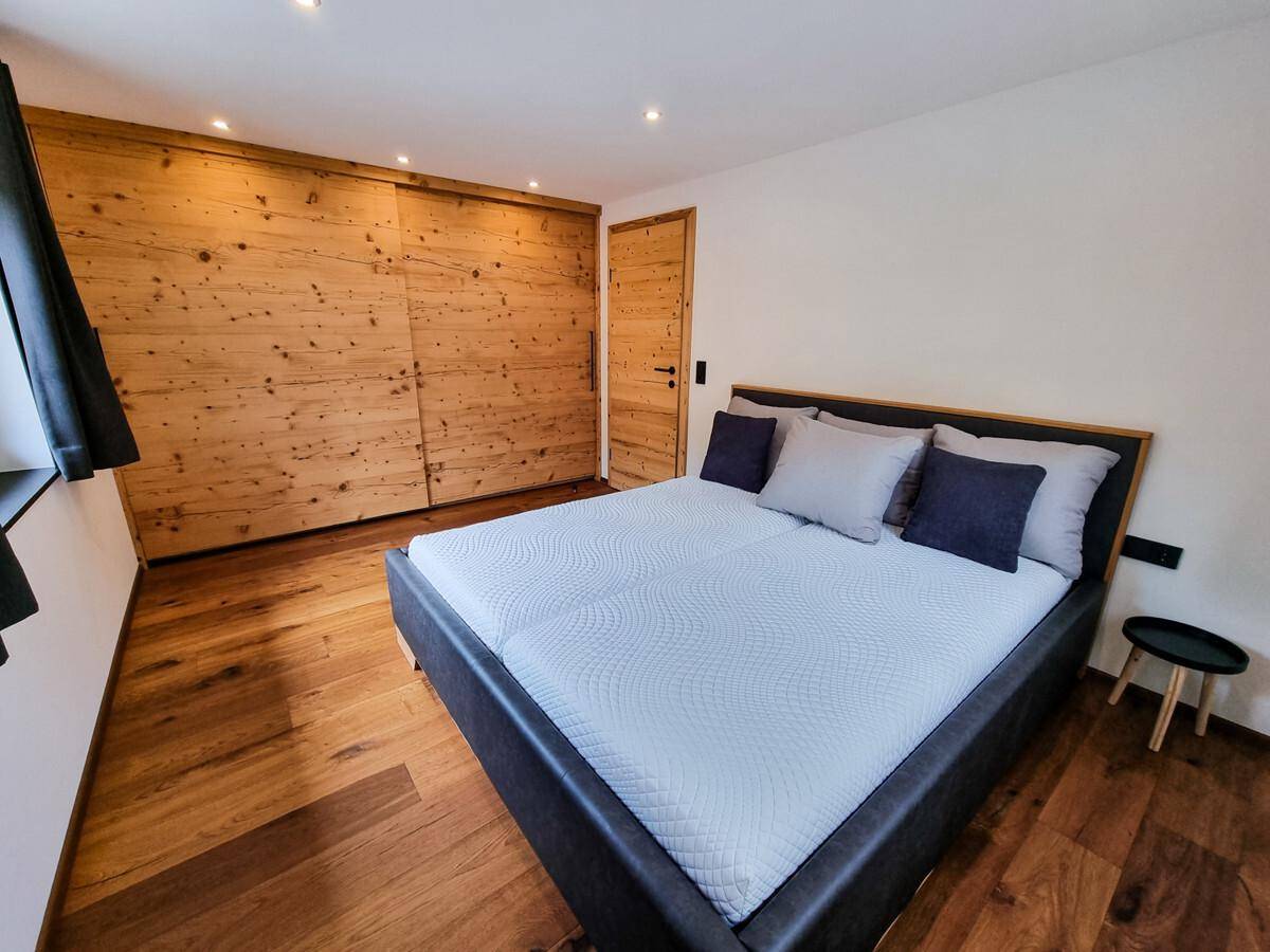 Gemütliches Schlafzimmer mit Holzboden, integrierten Holzschränken und modernem Doppelbett.