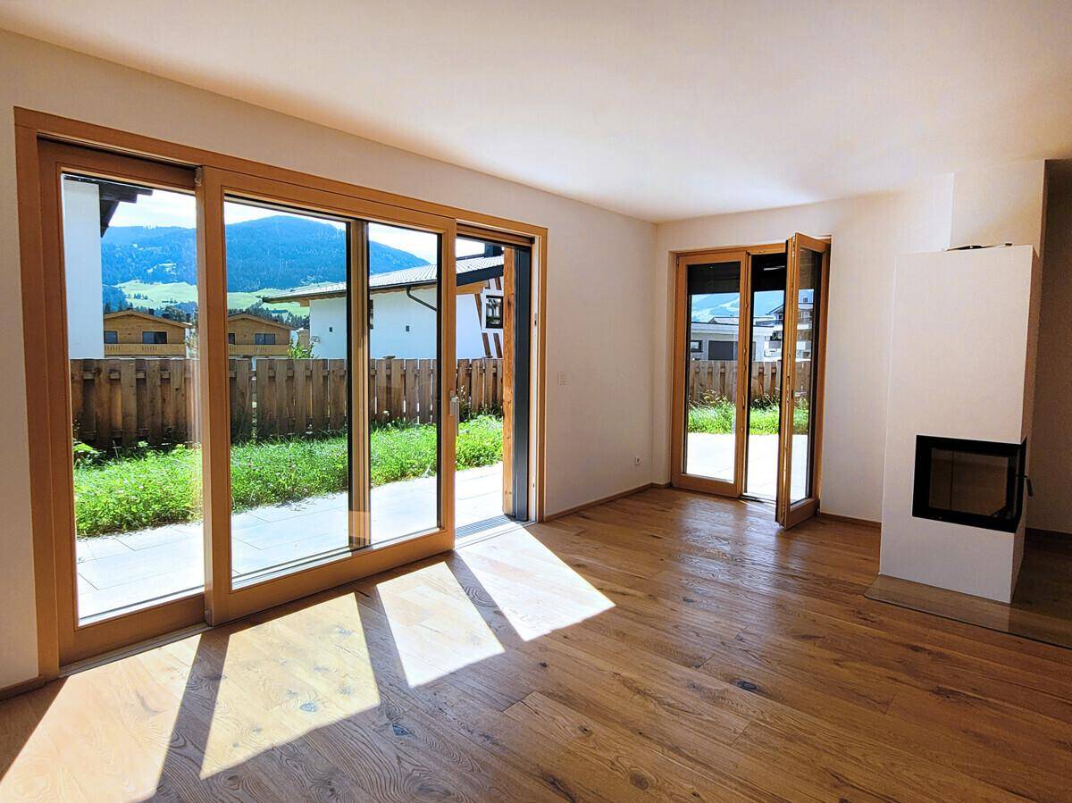 Lichtdurchfluteter Wohnbereich mit Holzboden, Kamin und großen Schiebetüren zum Garten.