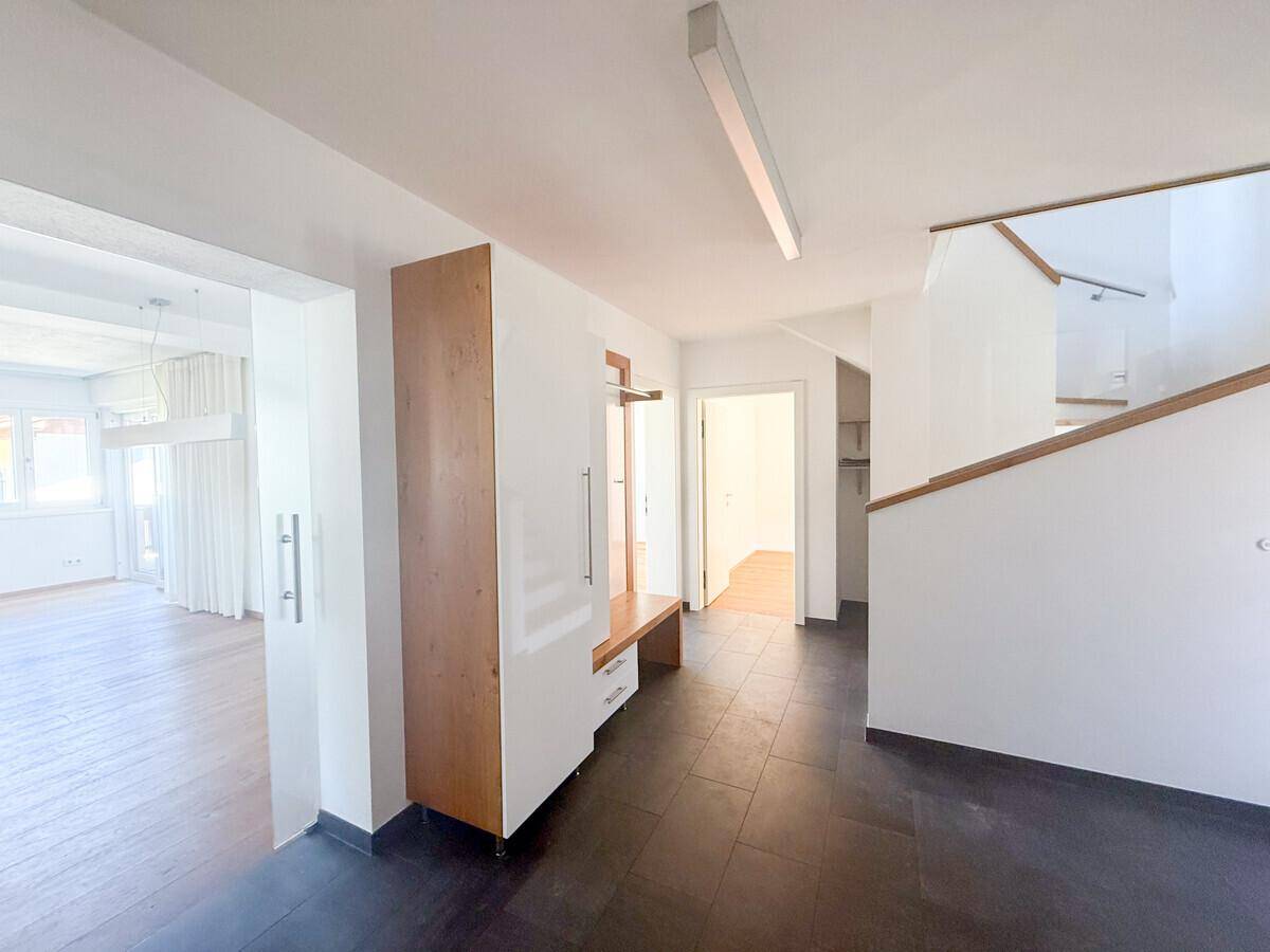 Heller Eingangsbereich mit Fliesenboden, Garderobe und offenem Treppenaufgang zum Obergeschoss.