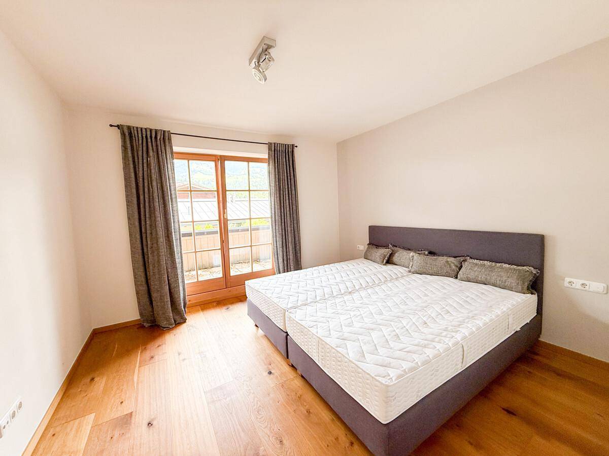 Gemütliches Schlafzimmer mit Holzboden, Doppelbett und Zugang zum Außenbereich.