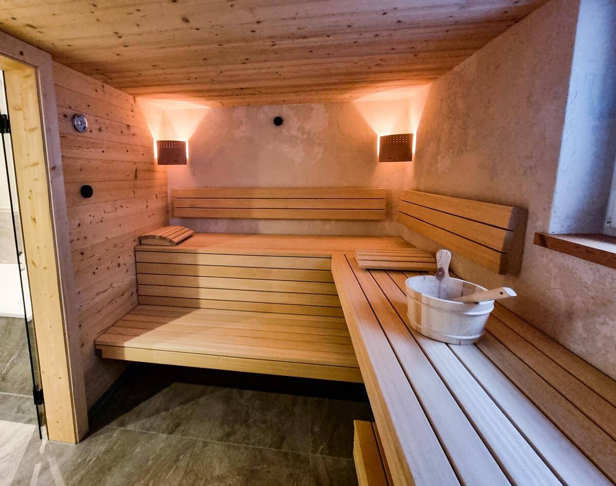 Gemütliche Holzsauna mit Sitzbänken, indirekter Beleuchtung und traditionellem Saunaeimer.
