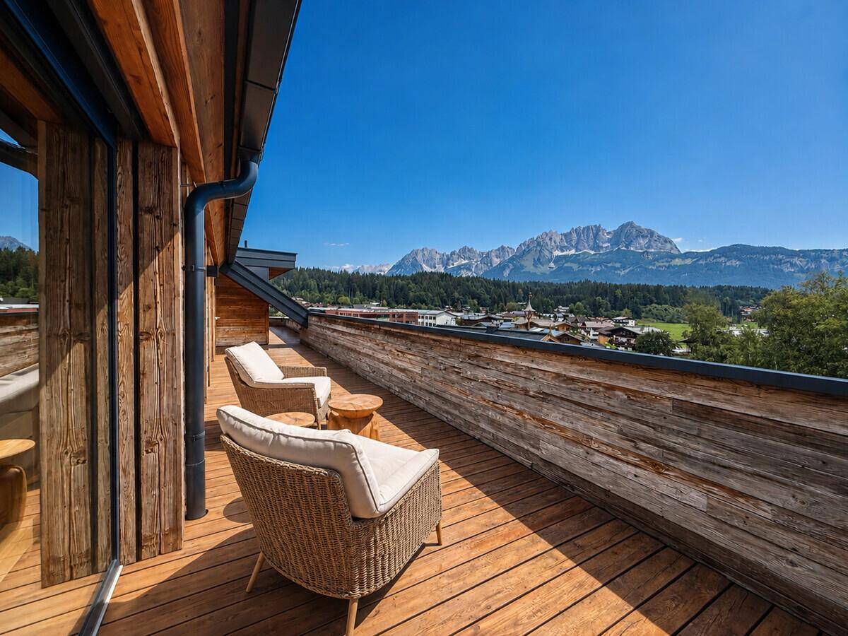Holzterrasse mit bequemen Sesseln und weitem Blick auf die umliegende Berglandschaft.