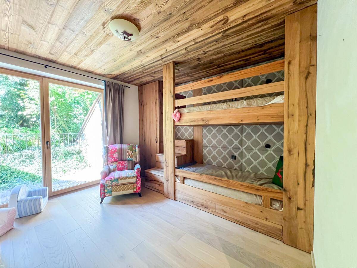 Kinderzimmer mit maßgefertigten Etagenbetten aus Holz und Zugang zum Garten.