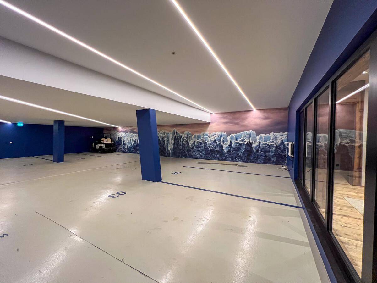 Geräumige Tiefgarage mit blauen Säulen und künstlerischer Wandgestaltung.