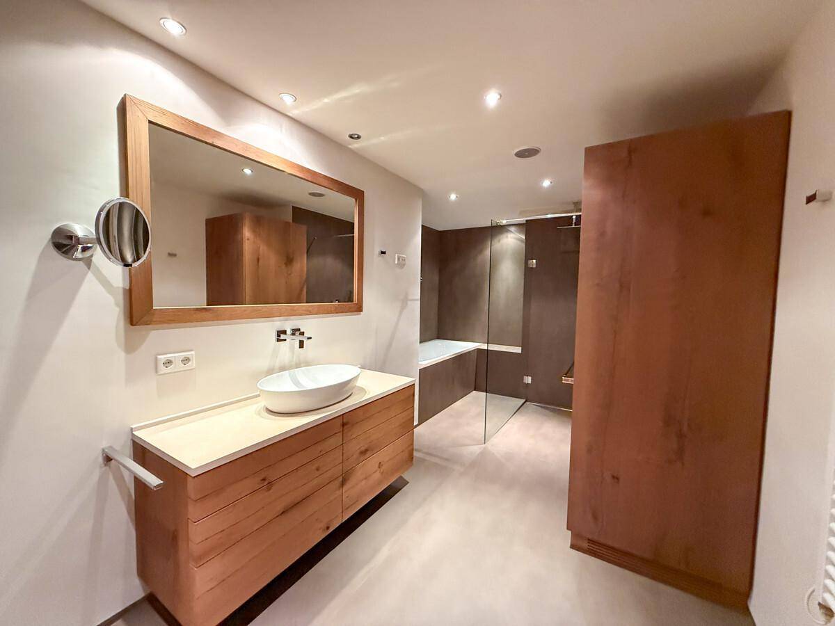 Modernes Badezimmer mit Holzwaschtisch, Aufsatzwaschbecken und begehbarer Dusche.