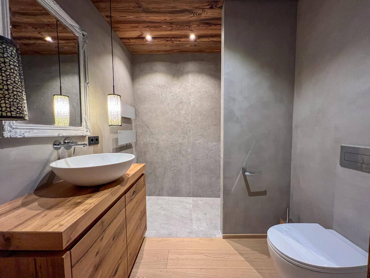 Modernes Badezimmer mit Holzwaschtisch, begehbarer Dusche und Wand-WC.