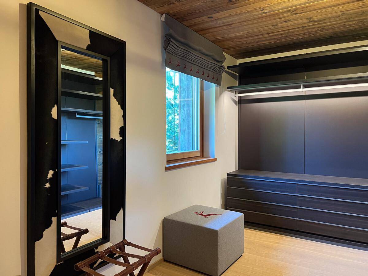 Moderner begehbarer Kleiderschrank mit Einbauschränken, Schubladen und großem Spiegel.