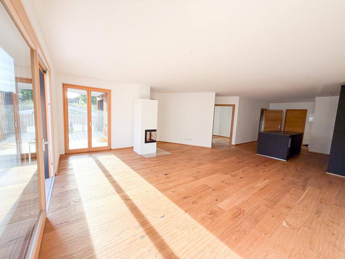 Heller Wohnbereich mit Holzboden, Kamin und Zugang zur Terrasse, bereit für die Einrichtung.