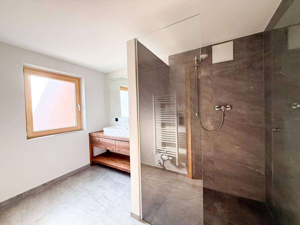 Modernes Badezimmer mit begehbarer Dusche, Holzwaschtisch und großformatigen Fliesen.