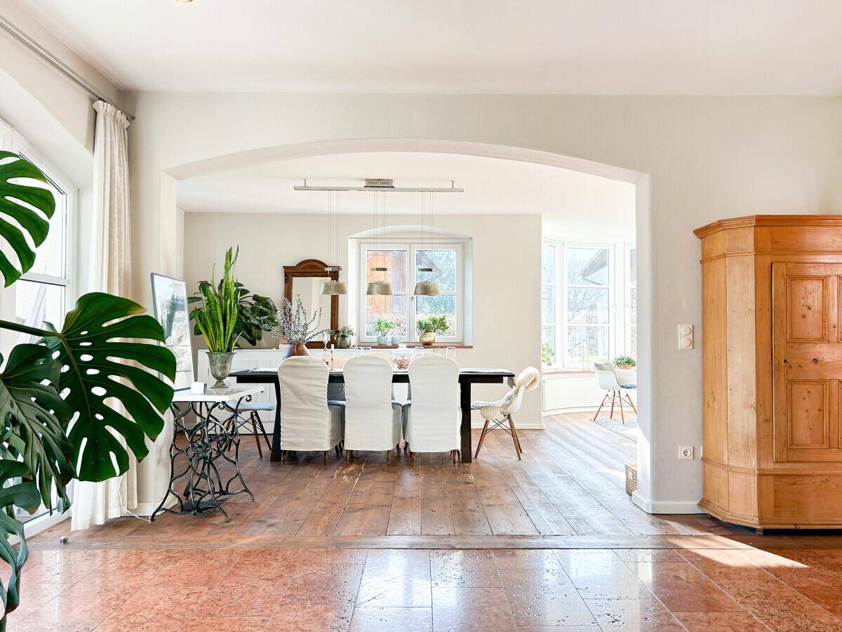 Eleganter Essbereich mit Holzboden, großem Esstisch und Durchgang zu weiteren hellen Räumen.