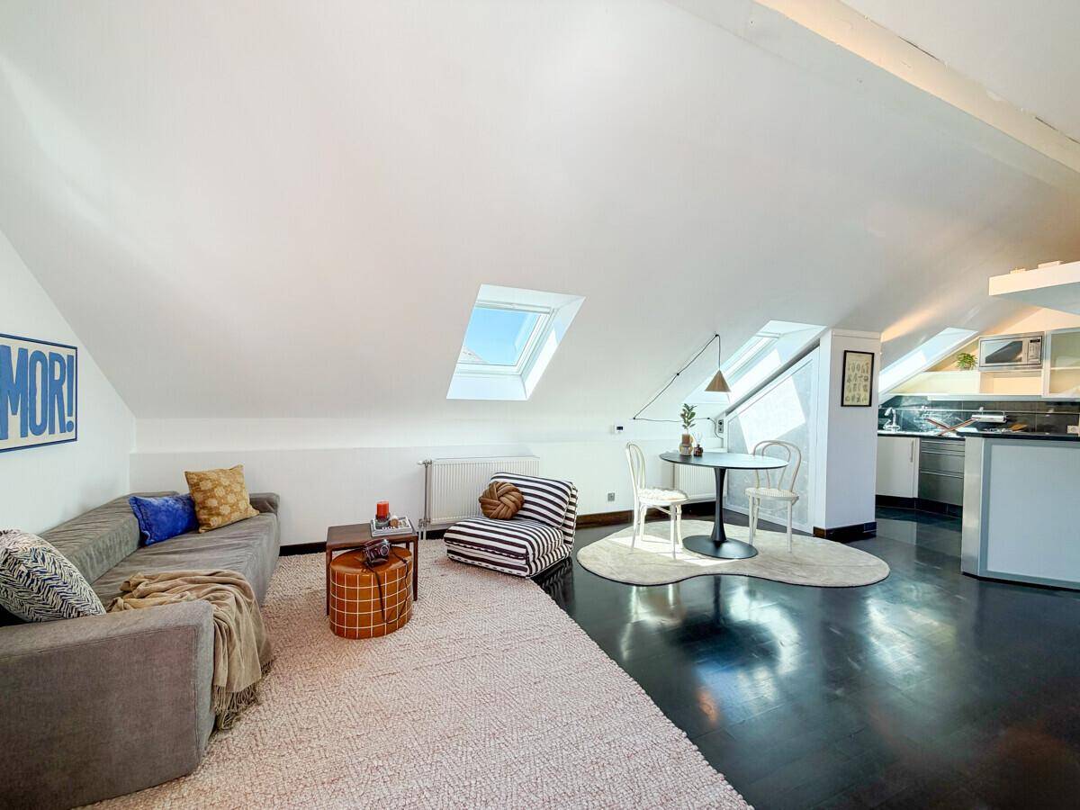 Gemütlicher Wohnbereich mit Sofa, Teppich und Essplatz unter den Dachschrägen mit Oberlichtern.
