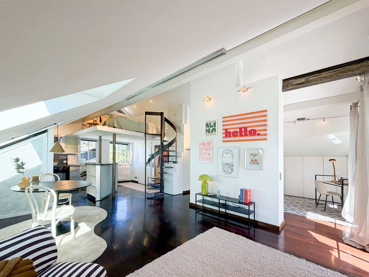 Offener Wohnbereich im Loft-Stil mit Wendeltreppe, Schlafgalerie und dunklem Holzboden.