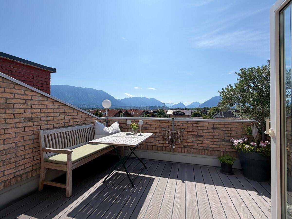 Geräumige Dachterrasse mit Holzboden, Sitzgelegenheiten und atemberaubendem Panoramablick auf die Berge.