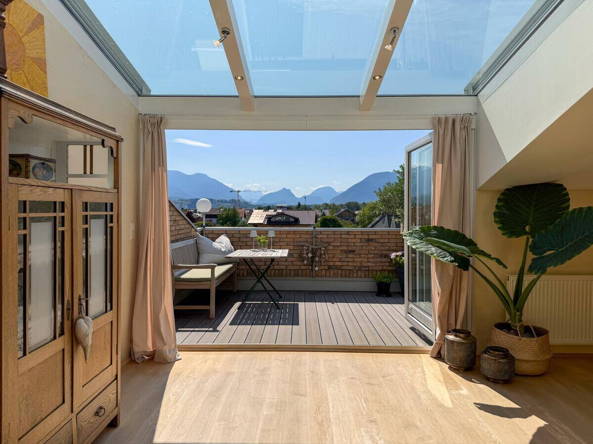 Lichtdurchfluteter Wintergarten mit Glasdach und direktem Zugang zur Terrasse mit Bergblick.