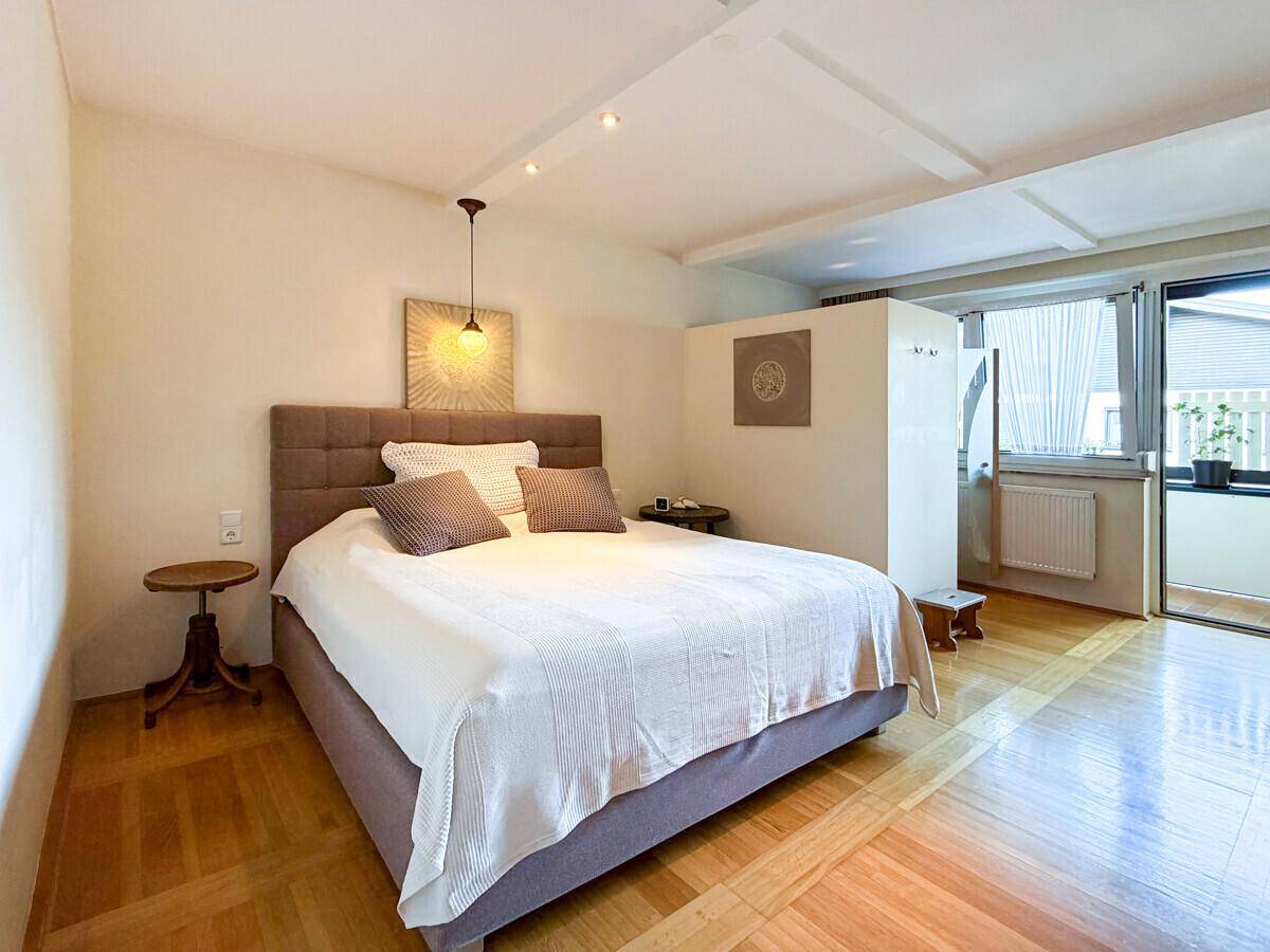 Gemütliches Schlafzimmer mit Doppelbett, Holzboden und Zugang zu einem kleinen Balkon.