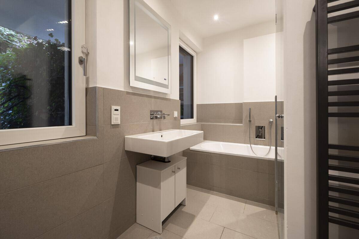Modernes Badezimmer mit Badewanne, Dusche, Einzelwaschbecken und Fenster.