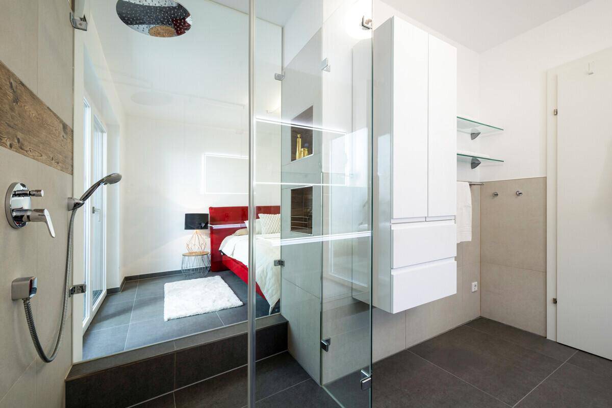Offener Duschbereich mit Glasabtrennung, direkt angrenzend an das Schlafzimmer für modernen Komfort.