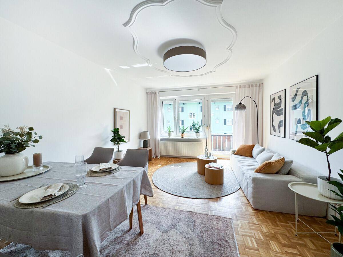 Heller Wohn- und Essbereich mit Parkettboden, stilvoller Einrichtung und Zugang zum Balkon.