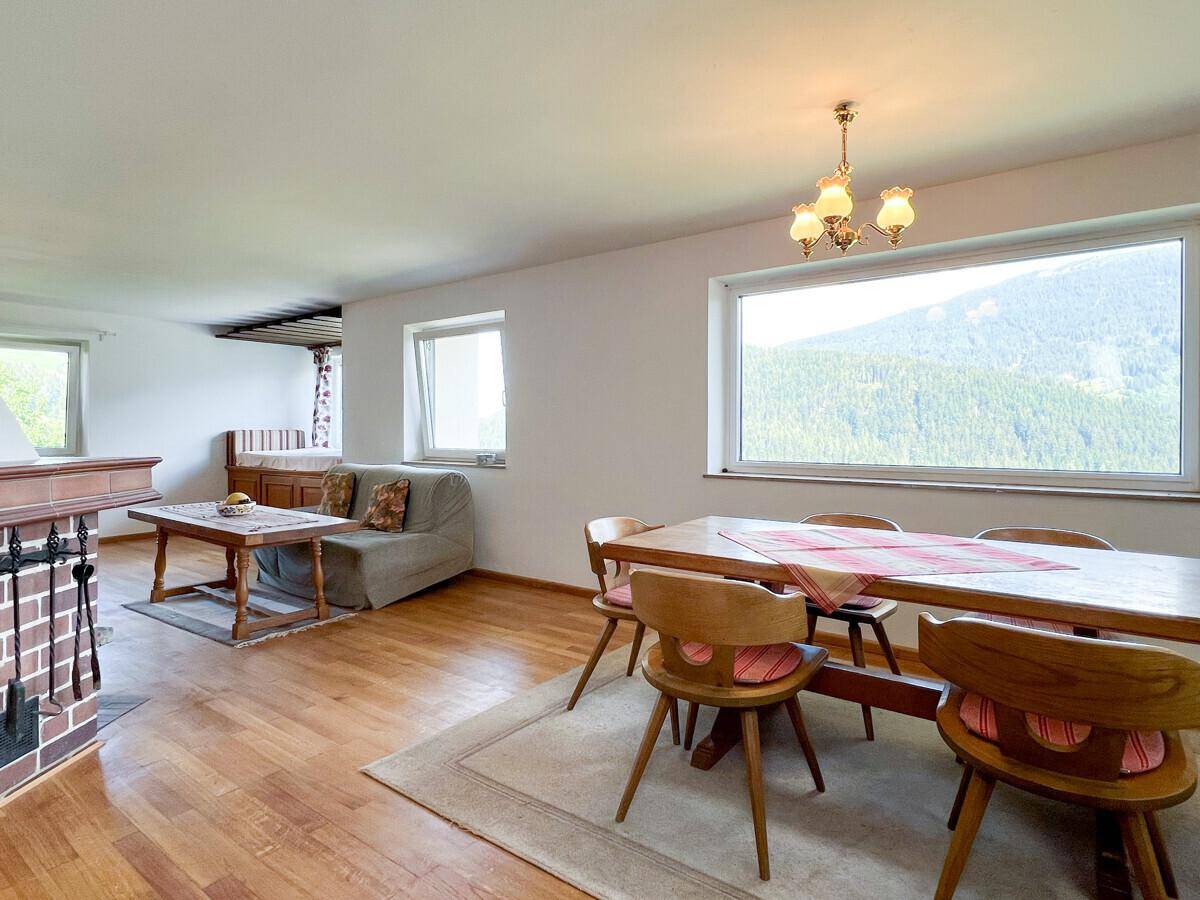 Heller Wohn-Essbereich mit Holzboden, traditionellen Möbeln und großem Fenster mit Bergblick.