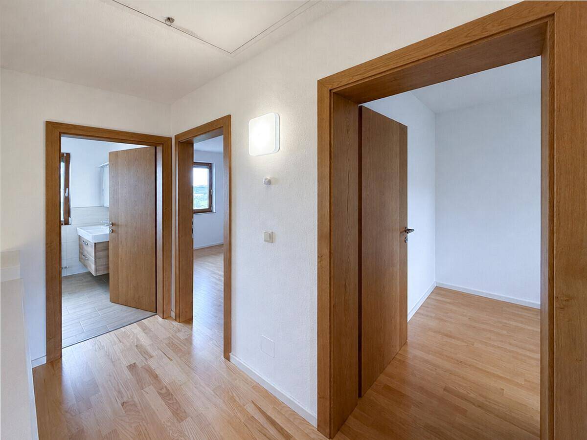 Heller Flur mit Holztüren und -rahmen, der zu verschiedenen Räumen führt.