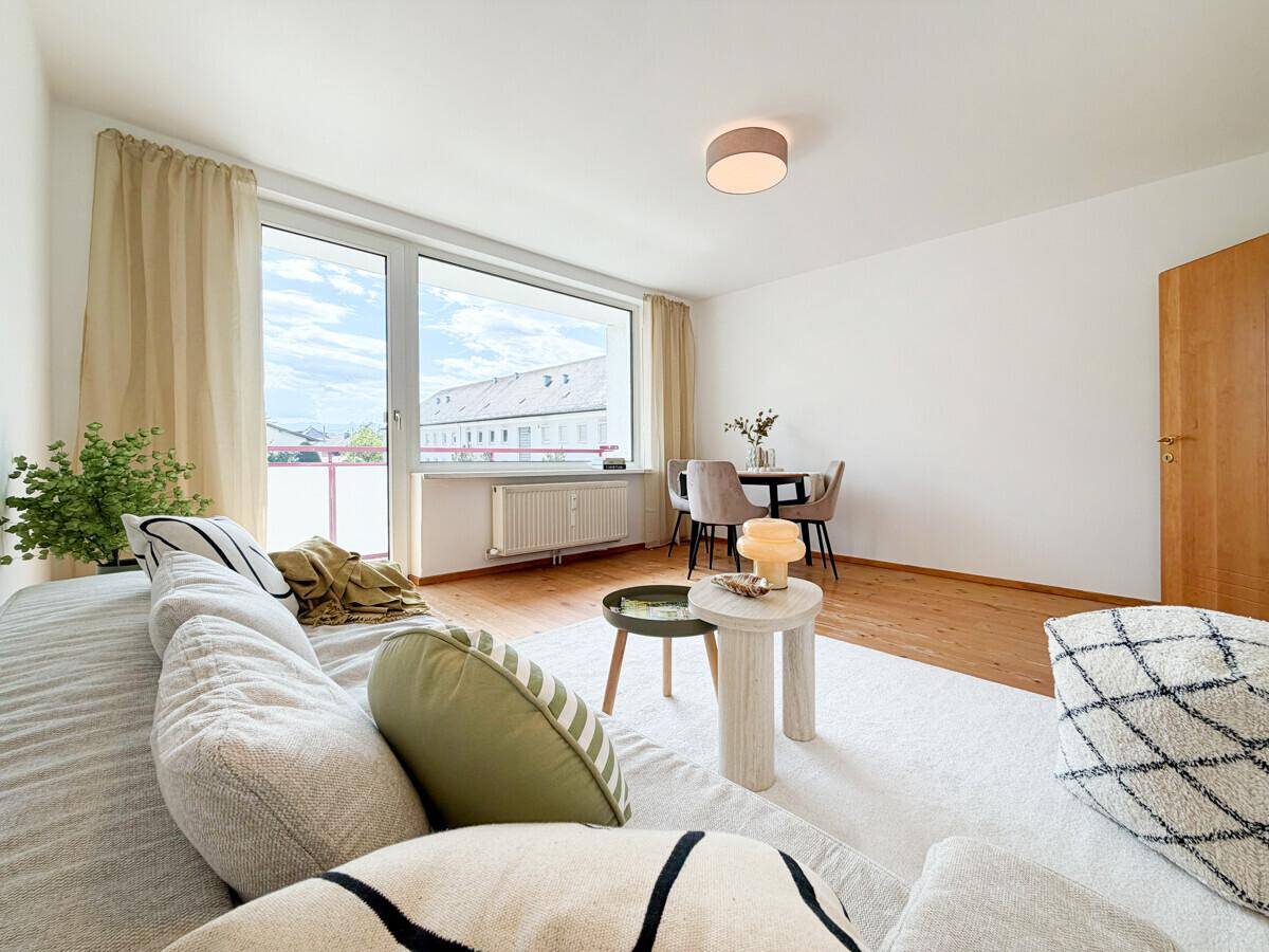Gemütlicher Wohnbereich mit Sofa, Esstisch und großen Fenstern für viel Tageslicht.