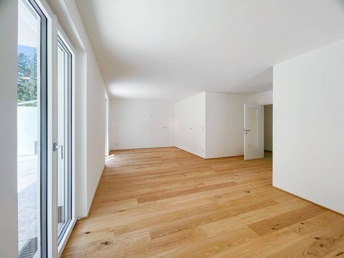 Geräumiges, unmöbliertes Wohnzimmer mit hellem Holzboden und großen Fenstern.