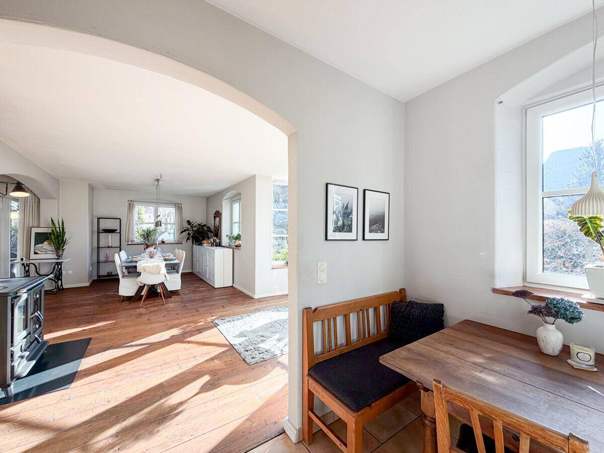 Gemütlicher Essbereich mit Holzbänken, einem Holzofen und Blick ins Grüne.