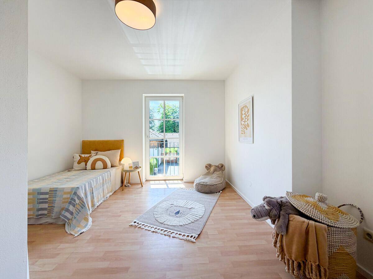Helles Kinderzimmer mit Laminatboden, Einzelbett und viel Tageslicht.