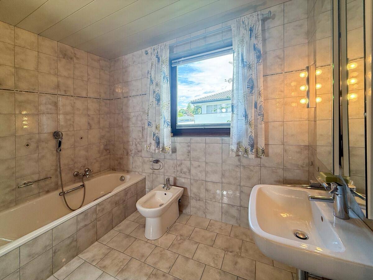 Helles Badezimmer mit Badewanne, Bidet und Fenster für natürliche Belüftung.