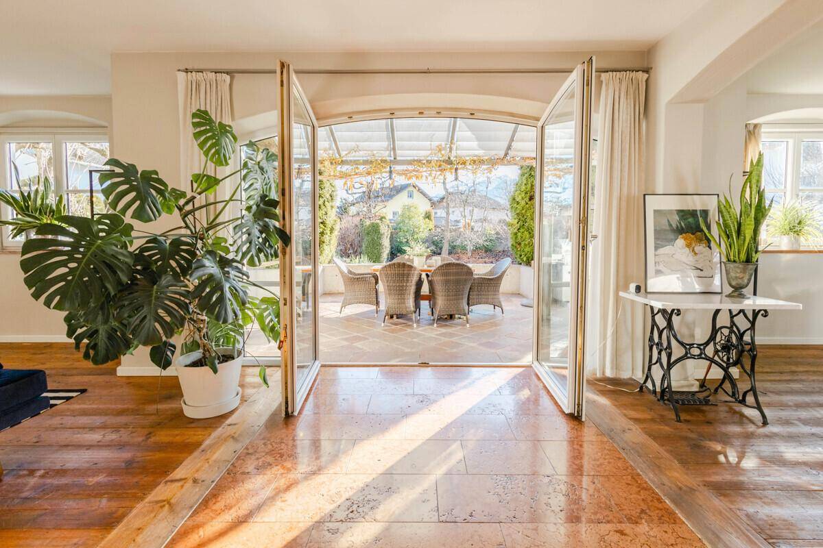 Heller Übergangsbereich zum Wintergarten mit großen Glastüren und Terrassenblick.