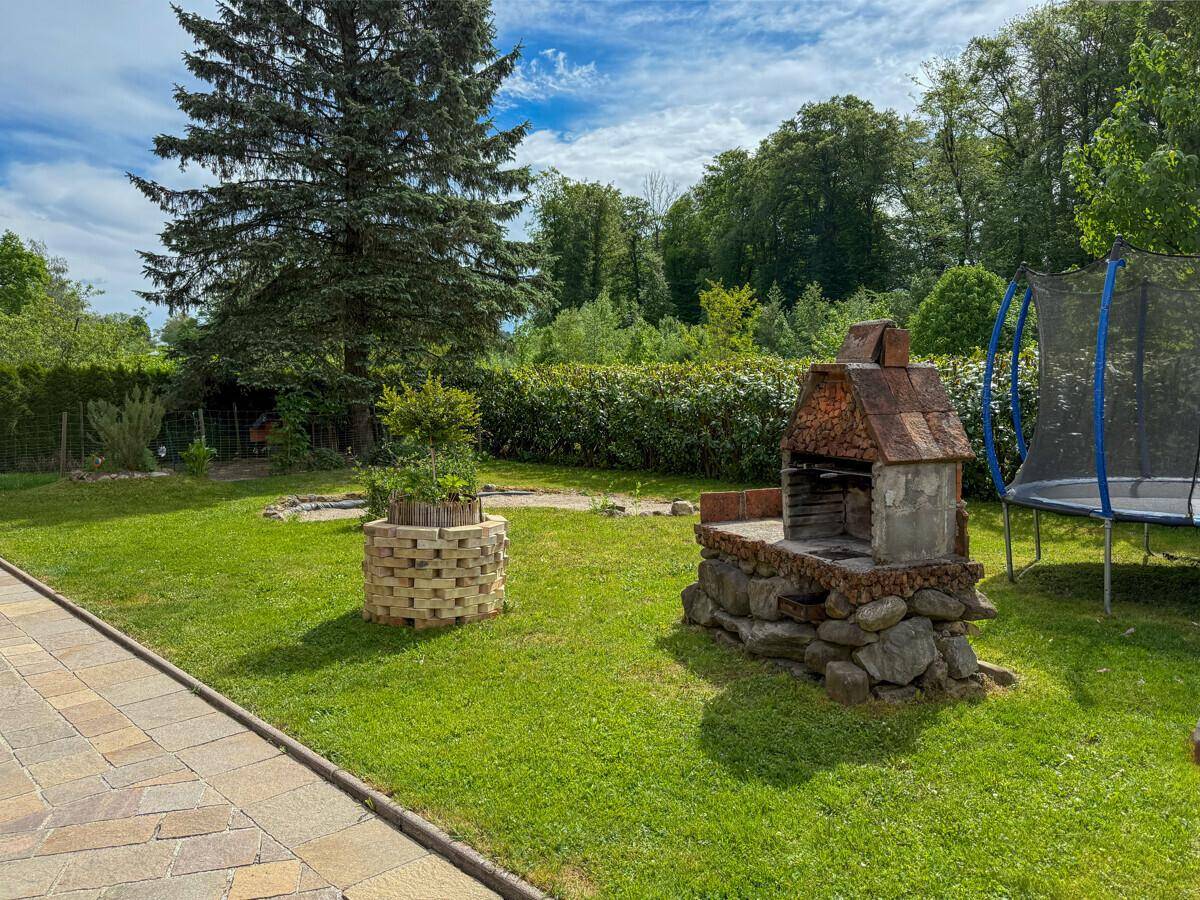 Großer Garten mit Grillplatz, Trampolin und viel Grünfläche für Freizeitaktivitäten.