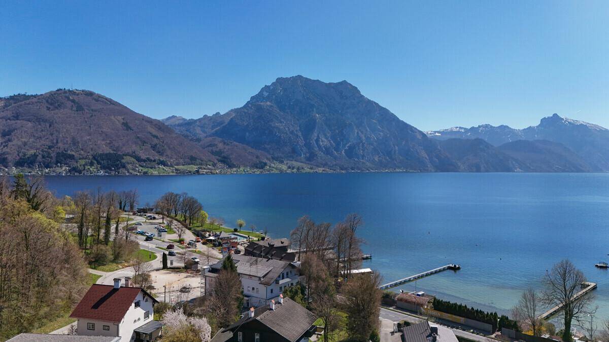 Panoramablick aus der Vogelperspektive auf den See, die umliegenden Berge und die Küstenbebauung.