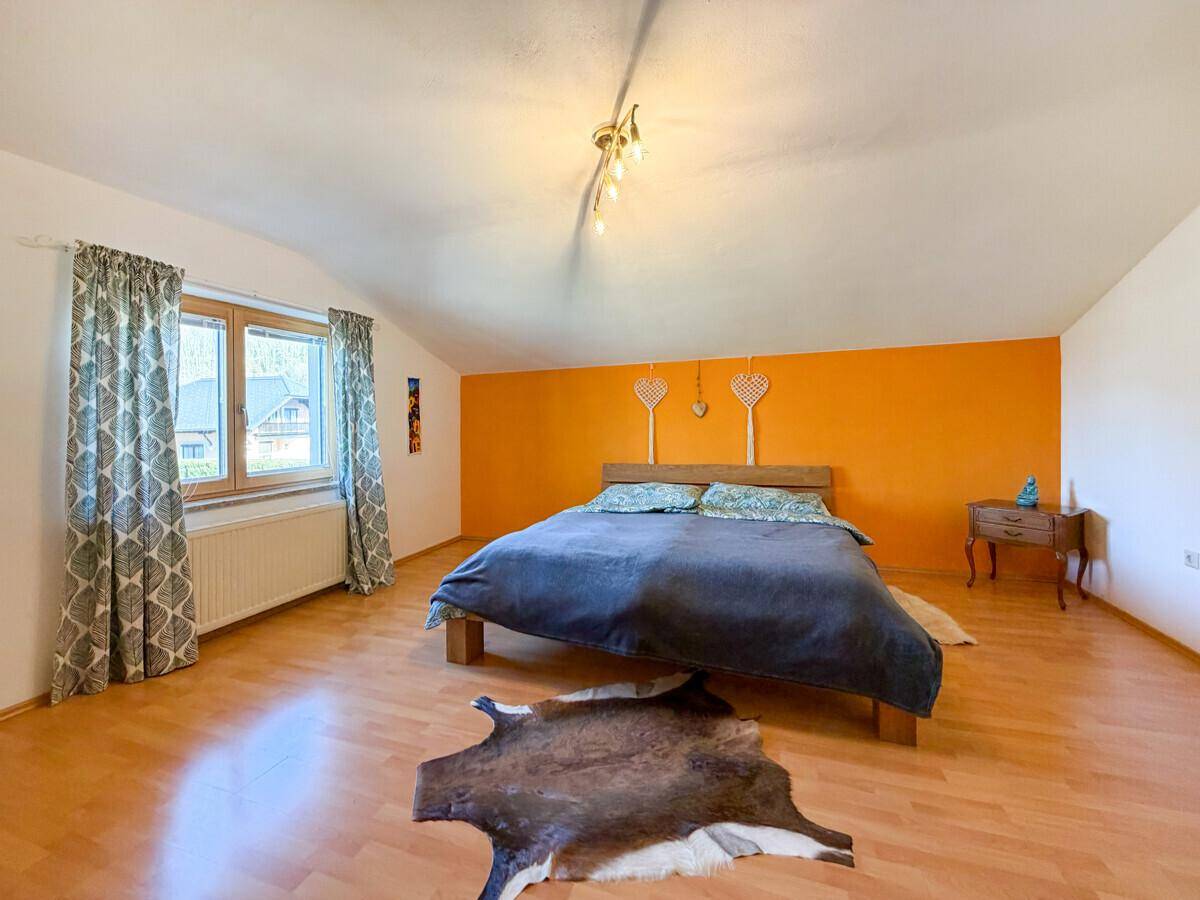Gepflegter Gartenbereich mit Rasenfläche und einem Sandkasten neben dem Haus mit Balkon.