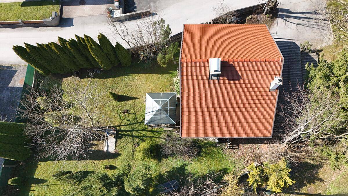 Draufsicht auf das Wohnhaus mit rotem Ziegeldach und dem dahinterliegenden Gartenbereich.